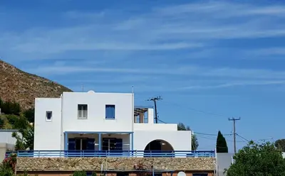 a white house with a blue fence around it at Zafeiris Apartments in Livadia