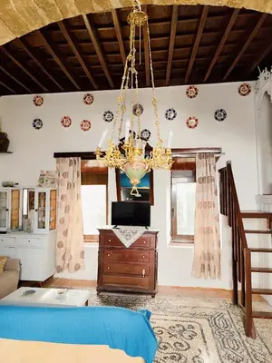 a living room with a chandelier and a tv at Stam Luxury Traditional House in Koskinou