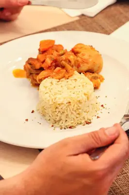 a white plate of food with rice and chicken at Delfinia Resort - All Inclusive in Kolimbia