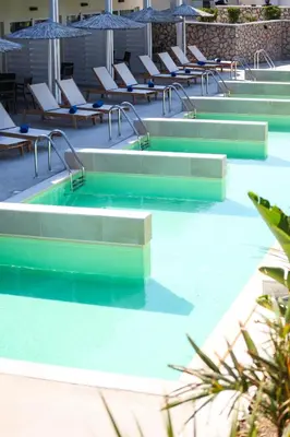 a swimming pool with lounge chairs in the water at Delfinia Resort - All Inclusive in Kolimbia
