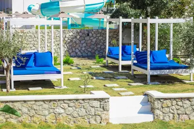 a group of blue swings with a water park in the background at Delfinia Resort - All Inclusive in Kolimbia