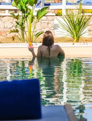 a woman sitting in the water in a swimming pool at Delfinia Resort - All Inclusive in Kolimbia