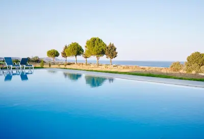 a swimming pool with chairs and the ocean in the background at Luxury Villa Trapezia in Afantou
