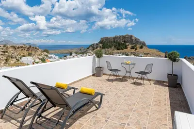 a patio with chairs and a table on a white wall at Flora Studios in Líndos
