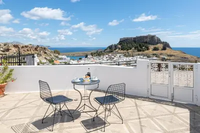 a patio with a table and chairs on a balcony at Flora Studios in Líndos