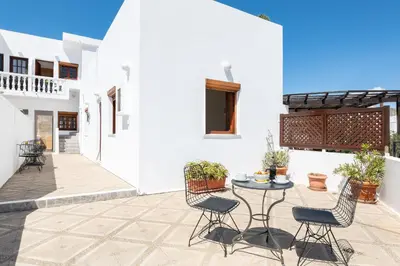 a courtyard with a table and chairs on a patio at Flora Studios in Líndos