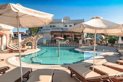 a pool with chairs and umbrellas in a hotel at Bright Star in Faliraki