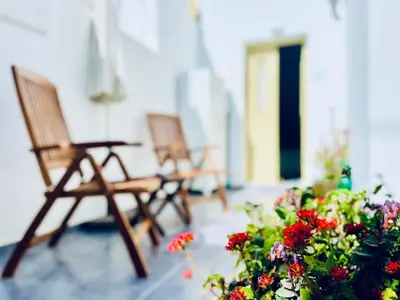 two wooden chairs and flowers on a porch at Aegli Apartments in Symi