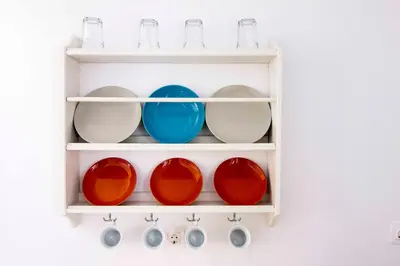 a white shelf with plates and bowls on it at Aegli Apartments in Symi