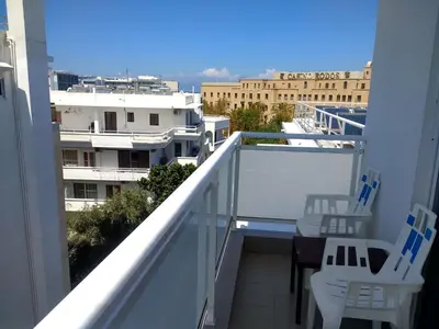 a balcony with white chairs and a table on it at International Hotel in Rhodes Town