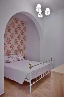a bedroom with a white bed with a floral wallpaper at Villa Mariza 1920 in Rhodes Town