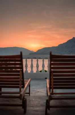 two benches sitting in front of a body of water at Anthi Maria Beach Apartments in Pefki Rhodes