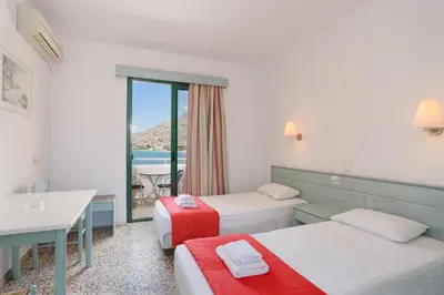 a hotel room with two beds and a balcony at Anthi Maria Beach Apartments in Pefki Rhodes