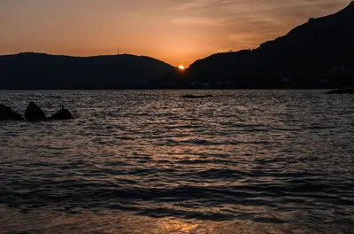 a sunset over a body of water with a boat at Anthi Maria Beach Apartments in Pefki Rhodes