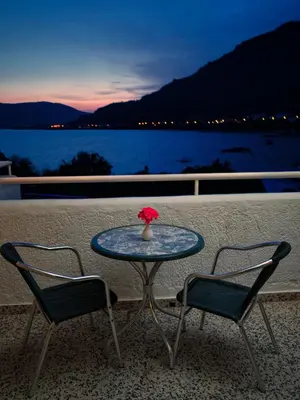 a table with two chairs and a vase with a flower at Anthi Maria Beach Apartments in Pefki Rhodes