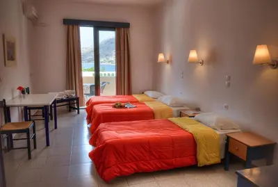 a hotel room with three beds and a table and a window at Anthi Maria Beach Apartments in Pefki Rhodes