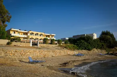 two chairs sitting on a beach next to a building at Anthi Maria Beach Apartments in Pefki Rhodes