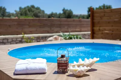 a table with towels and a candle next to a swimming pool at Emerald Dream Apartment in Faliraki