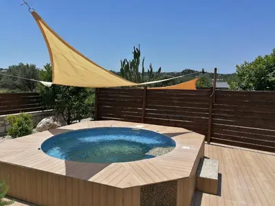 a hot tub on a wooden deck with a hammock at Emerald Dream Apartment in Faliraki