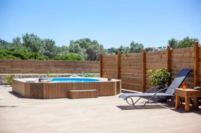 a backyard with a swimming pool and a wooden fence at Emerald Dream Apartment in Faliraki
