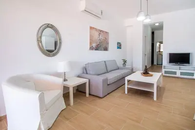 a living room with a couch and a tv at Emerald Dream Apartment in Faliraki
