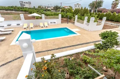 a swimming pool in a yard with chairs and a patio at Villa Dimitra Gennadi in Gennadi