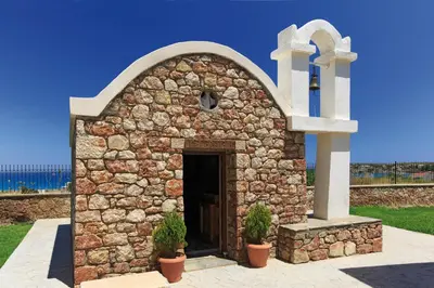a small stone church with two plants in front of it at Atlantica Mikri Poli Rhodes in Kolimbia