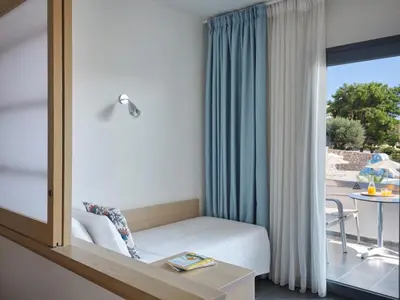 a room with a bed and a window with a table at Atlantica Mikri Poli Rhodes in Kolimbia