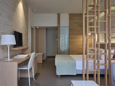 a hotel room with a bed and a desk and a room at Atlantica Mikri Poli Rhodes in Kolimbia