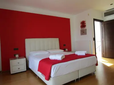 a bedroom with a white bed with a red wall at Villa Anastasia in Psinthos