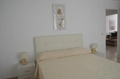 a white bedroom with a bed and a vase with a flower at Anthi City Center Apartment in Rhodes Town