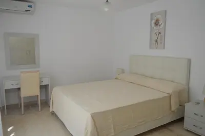 a white bedroom with a bed and a desk at Anthi City Center Apartment in Rhodes Town