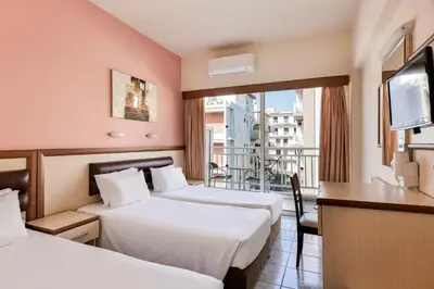 a hotel room with two beds and a balcony at Pearl Hotel in Rhodes Town