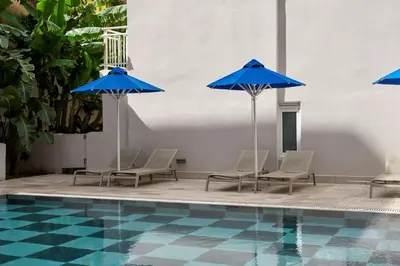 a group of chairs and umbrellas next to a pool at Pearl Hotel in Rhodes Town
