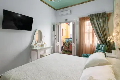 a bedroom with a bed and a television on the wall at Marika's Deluxe Rooms in Symi