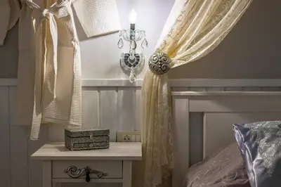 a bedroom with a bed and a window with curtains at Marika's Deluxe Rooms in Symi