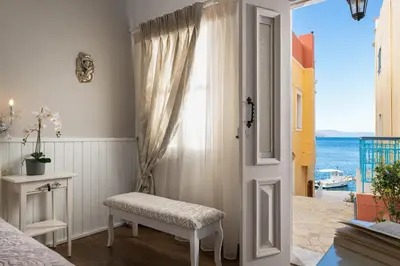 a bedroom with a door open to a view of the ocean at Marika's Deluxe Rooms in Symi