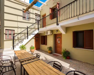 an outdoor patio with a wooden table and chairs at New Town Apartments in Rhodes Town