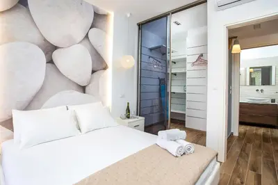 a bedroom with a large white bed and a bathroom at Yianna's Flat in Faliraki