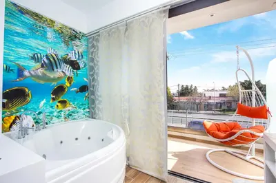a bathroom with a bath tub and a large window at Yianna's Flat in Faliraki