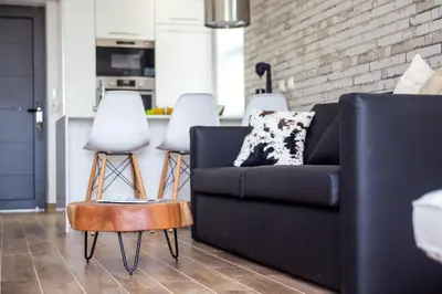 a living room with a black couch and two white stools at Yianna's Flat in Faliraki