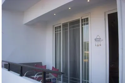 a balcony with a sliding glass door with red chairs at Seascape Apartment with Private Balcony in Faliraki in Faliraki