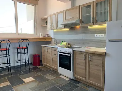 a kitchen with white appliances and wooden cabinets at Seascape Apartment with Private Balcony in Faliraki in Faliraki
