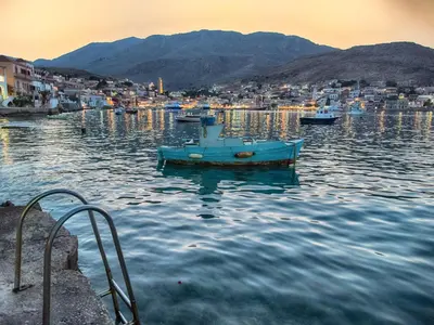 a blue boat in the water near a city at Aretanassa Hotel in Halki