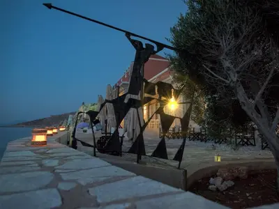 a building with lights on the side of the water at night at Aretanassa Hotel in Halki