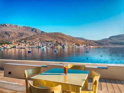 a table and chairs with a view of a body of water at Aretanassa Hotel in Halki