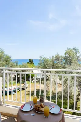 a table with plates of food and orange juice on a balcony at Stelios studios in Archangelos