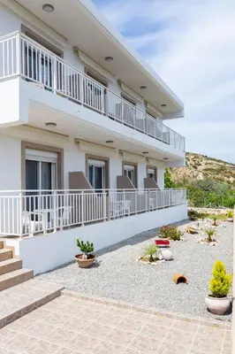 a white house with a balcony and some plants at Stelios studios in Archangelos