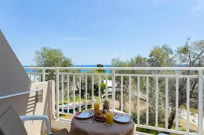 a table on a balcony with a view of the ocean at Stelios studios in Archangelos