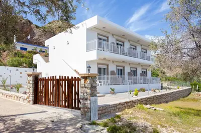 a white house with a gate and a fence at Stelios studios in Archangelos